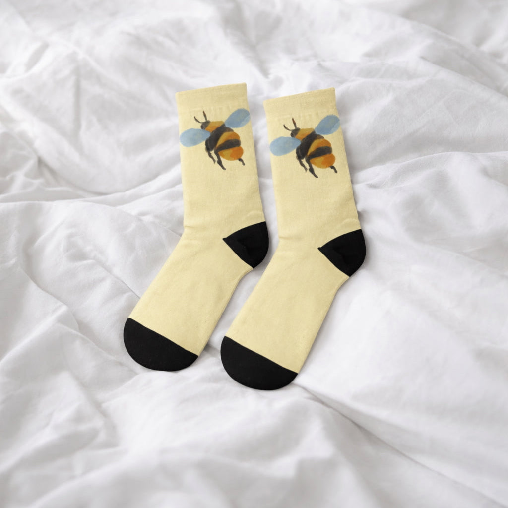 Pair of socks with bee design on a white fabric background