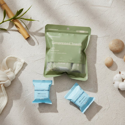 Compressed towels in green and blue packaging on a textured surface with natural elements.
