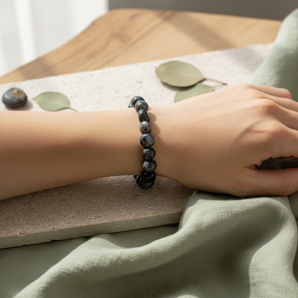 Person wearing a black stone bead bracelet on a light background