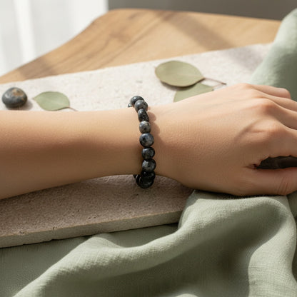 Person wearing a black stone bead bracelet on a light background
