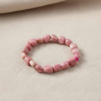 Pink stone bead bracelet on a beige fabric background