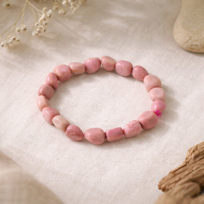 Pink natural stone beaded bracelet on a beige fabric background