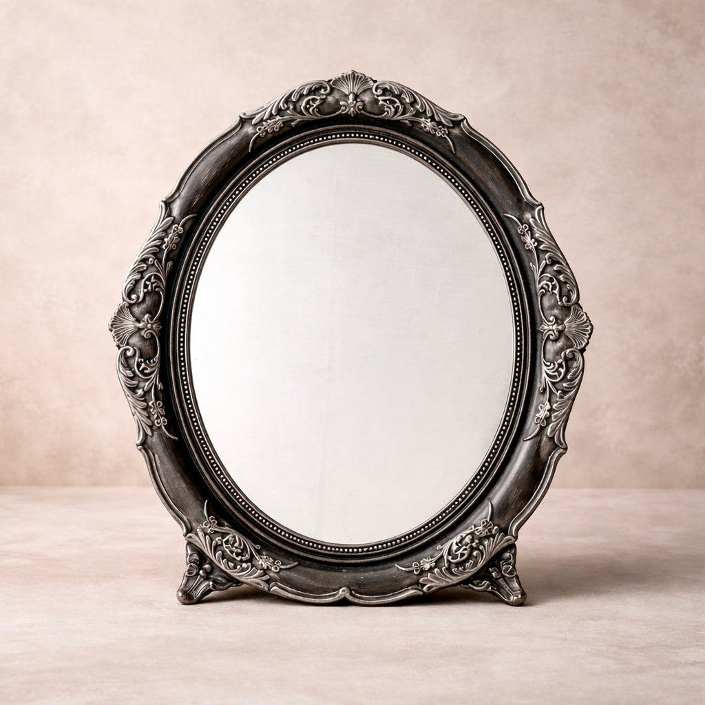 Decorative oval mirror with intricate black frame on a beige background