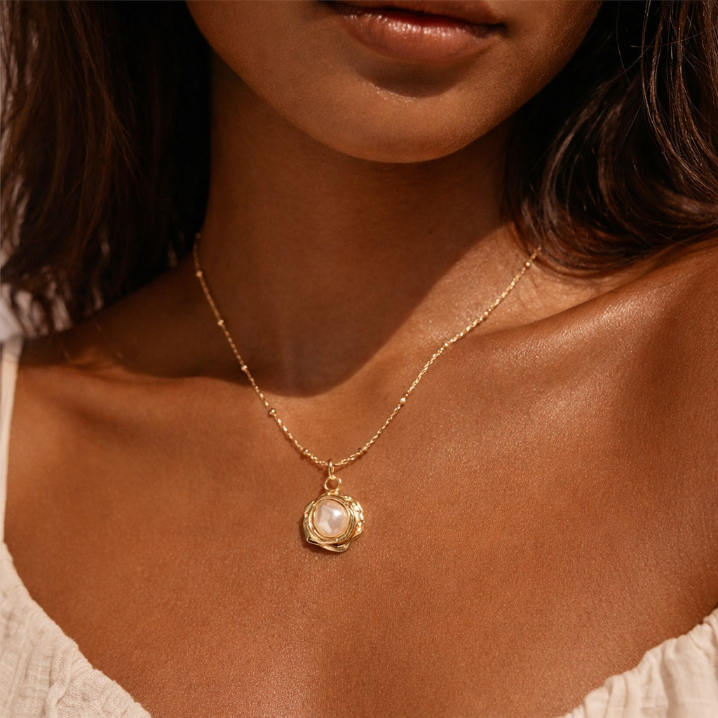 Close-up of a woman wearing a gold necklace with a pendant.