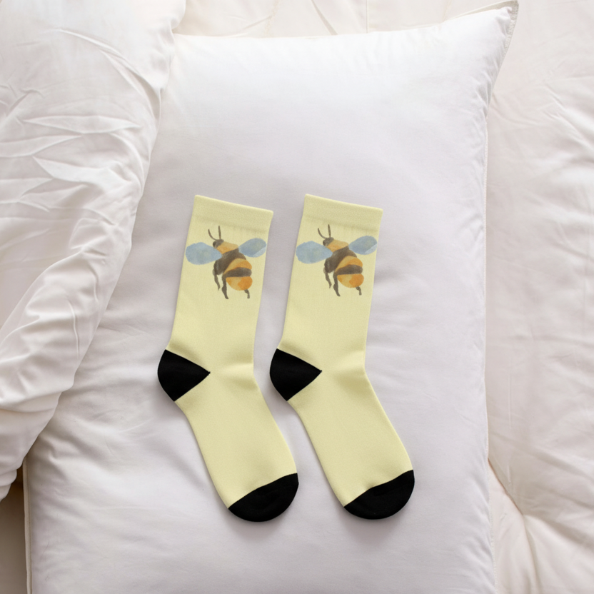 White pillow with yellow socks featuring bee design on a white background