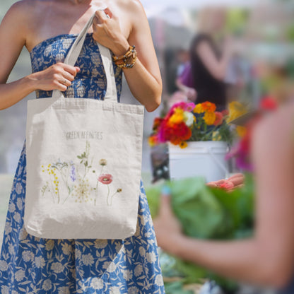 Woman holding a tote bag with floral design in an outdoor setting